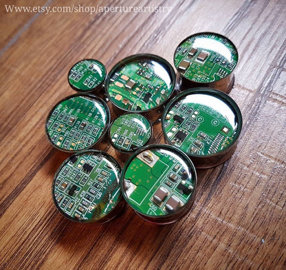 Circular green circuit boards plug earrings on a wooden surface