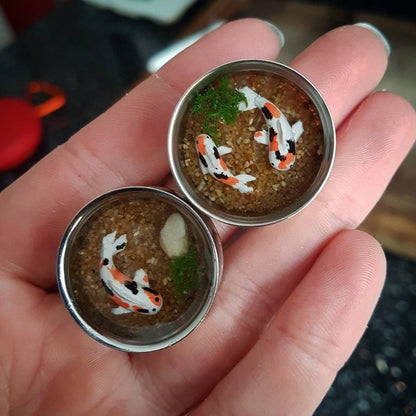Koi fish pond plugs, polymer clay and resin in a stainless steel plug shown against a hand