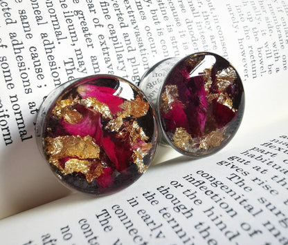 rose and gold style plug earrings against a book with text