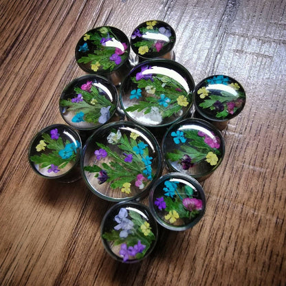  round plug earrings with pressed flowers on a wooden surface