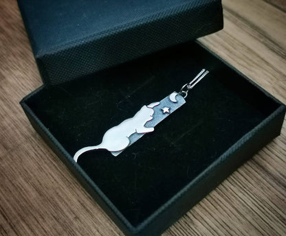 Silver keychain with a cat design in an open black box on a wooden surface