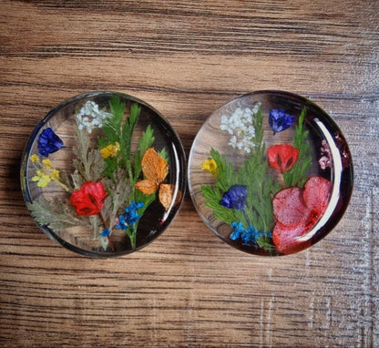  round plug earrings with pressed flowers on a wooden surface