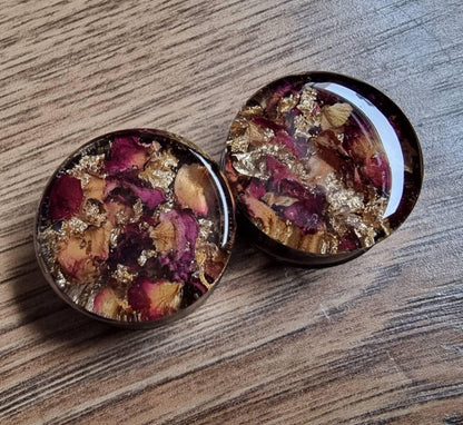 plug earrings with rose and gold accents against a wood backdrop