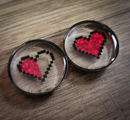 Pixelated heart designs plug earrings objects on a wooden surface