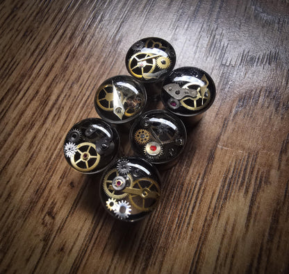 All sizes Steampunk steel tunnel clockwork plug earring against a wooden floor
