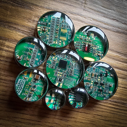 Green circuit boards plug earrings arranged on a wooden surface