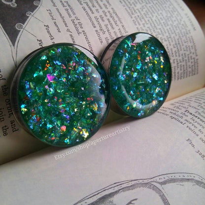 Green glittery earrings on an open book