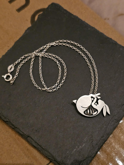 Silver necklace with a rabbit pendant on a dark slate surface