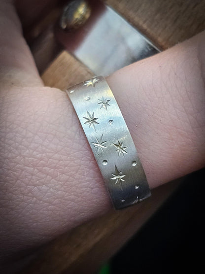 Silver ring with star patterns on a finger