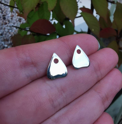 planchette shaped earrings against a hand 